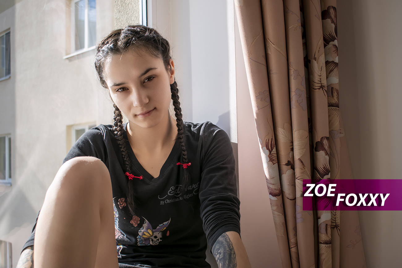 Zoe Foxxy poses near a hotel window while receiving oral sex in a 4K VR POV scene with spatial audio.